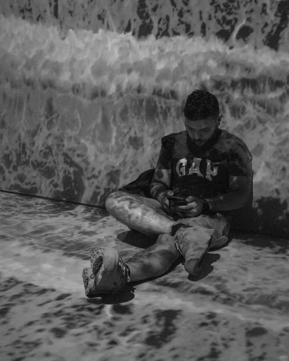 um homem sentado na praia olhando para o seu telefone celular