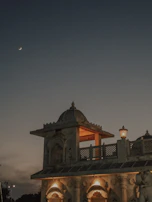 Evening view of Mukteshwar Jain temple illuminated softly with mountains in the background.