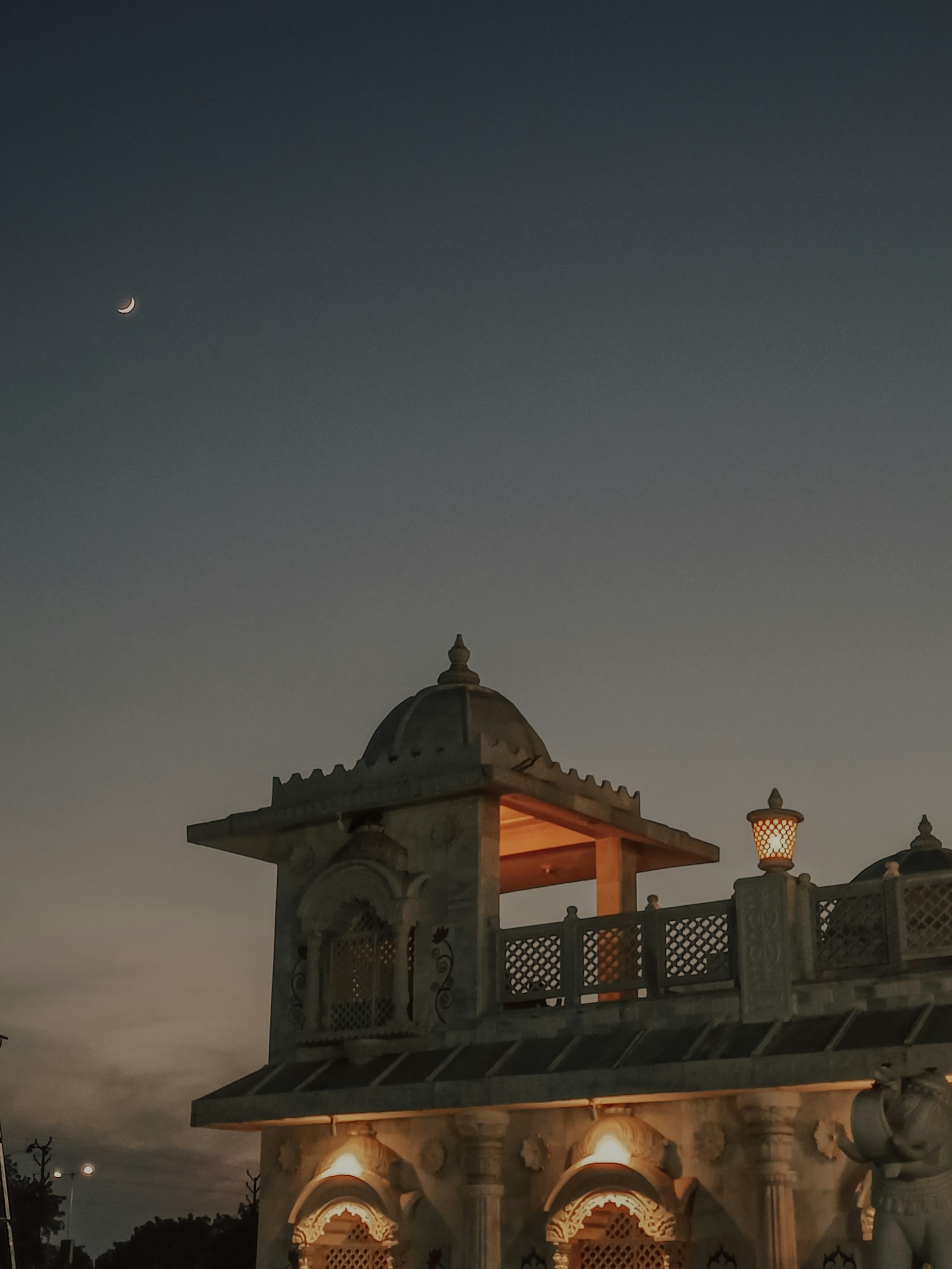 A serene evening view of the Iskcon Bijwasan temple glowing warmly under the twilight sky.