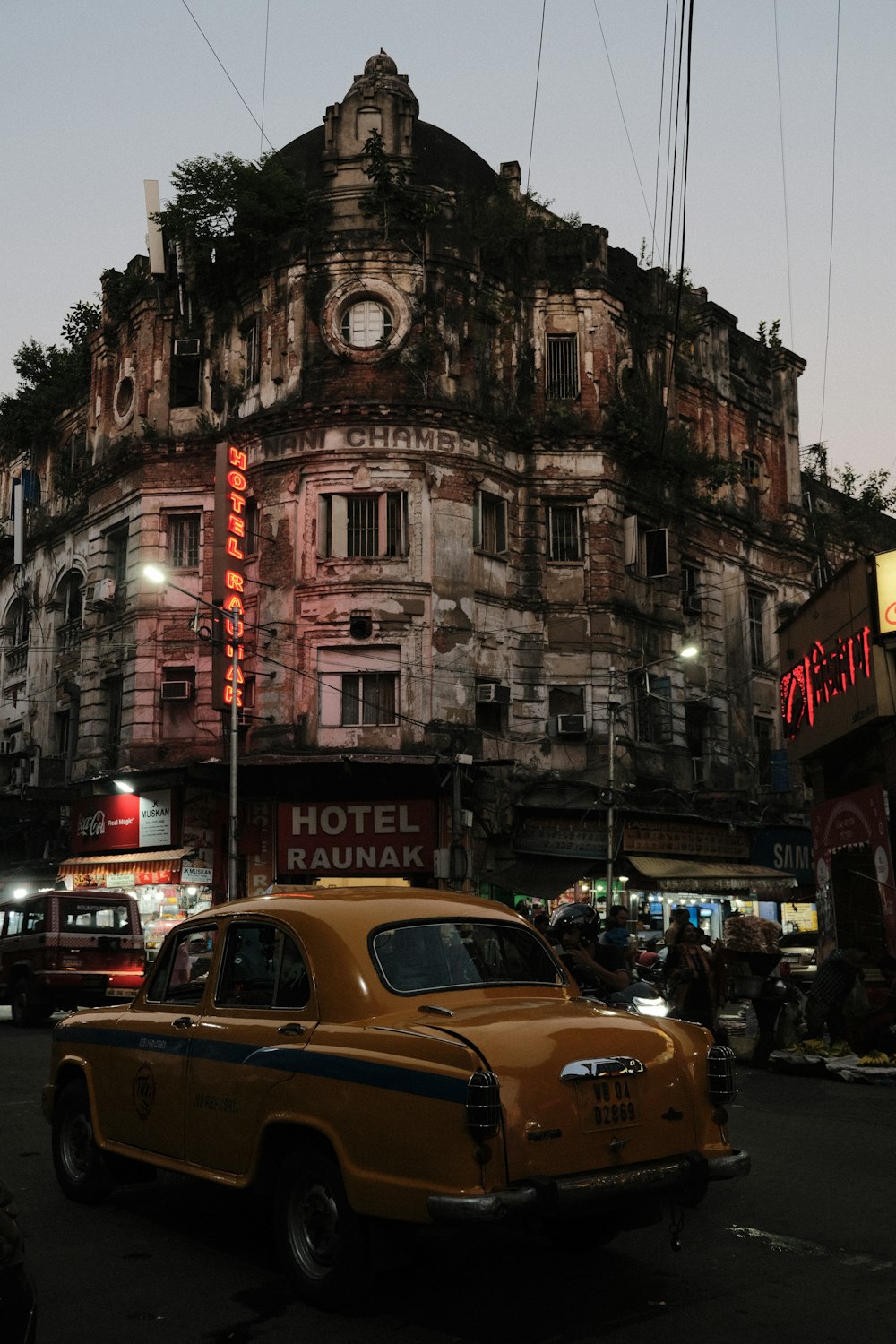 a yellow car driving down a street next to a tall building