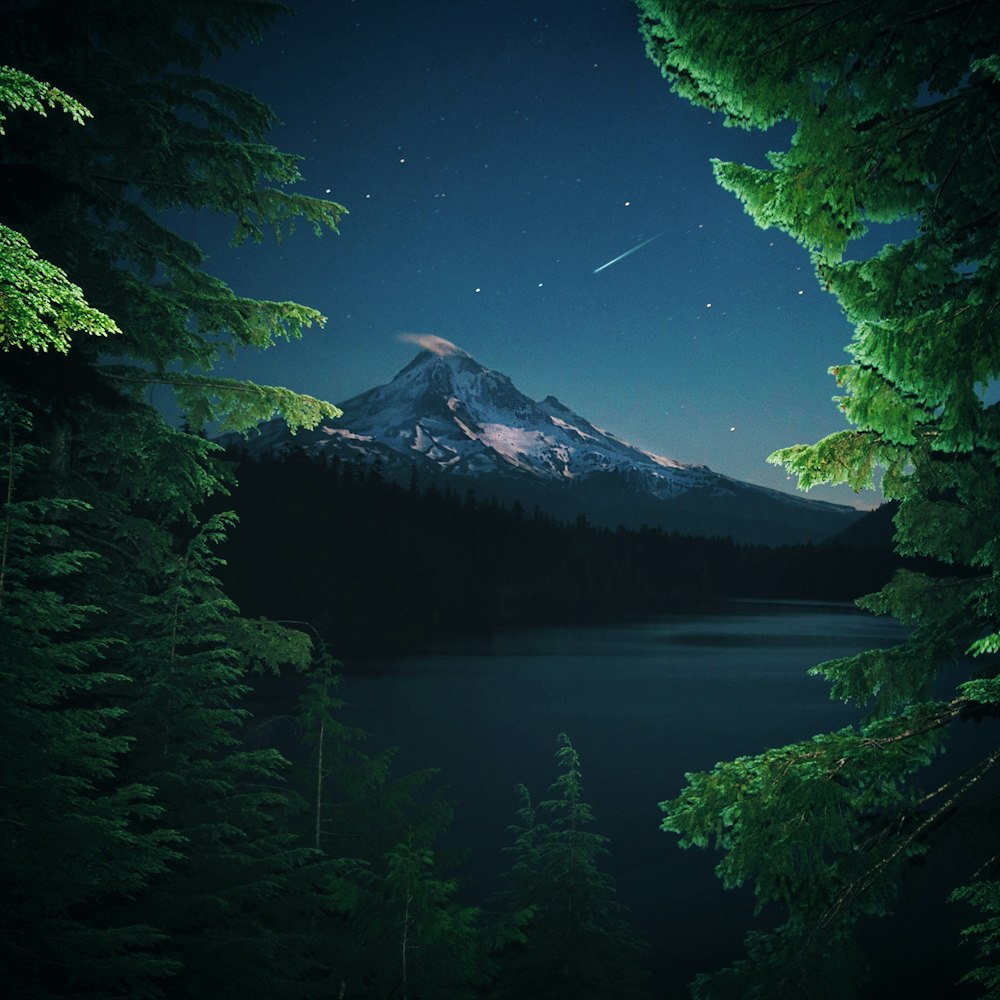 a night scene of a mountain and a lake
