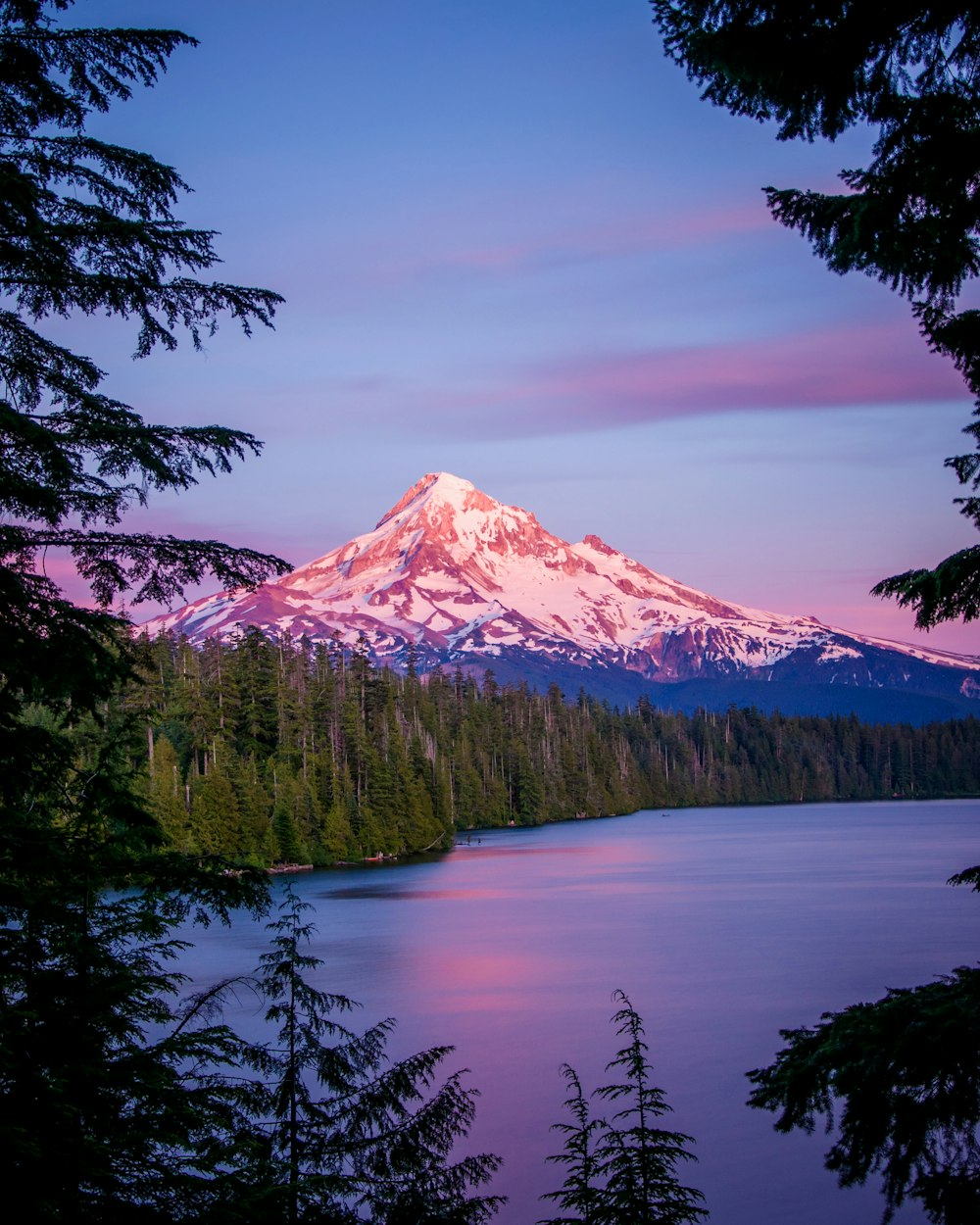 a snow covered mountain towering over a lake