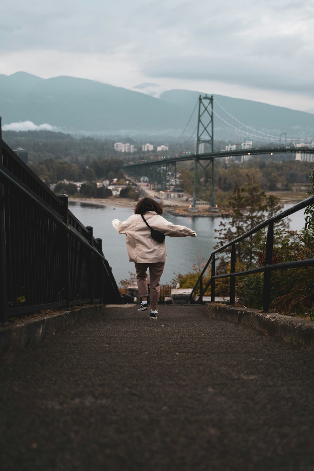 a person is walking down a path near a bridge