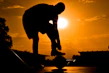Close-up of a person tying their running shoes on a sunlit trail.
