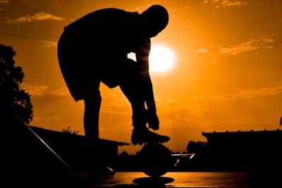 Runner tying shoelaces outdoors with a city park background at sunrise.