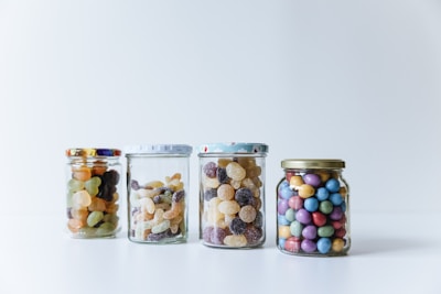 An assortment of colorful candies displayed in glass jars on a bright background.