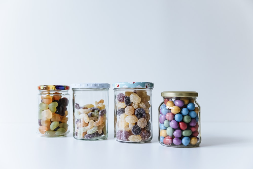 three glass jars filled with different types of candy