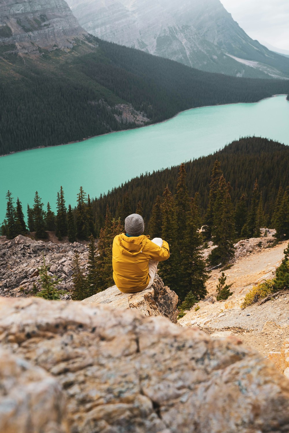 a person sitting on a rock overlooking a lake
