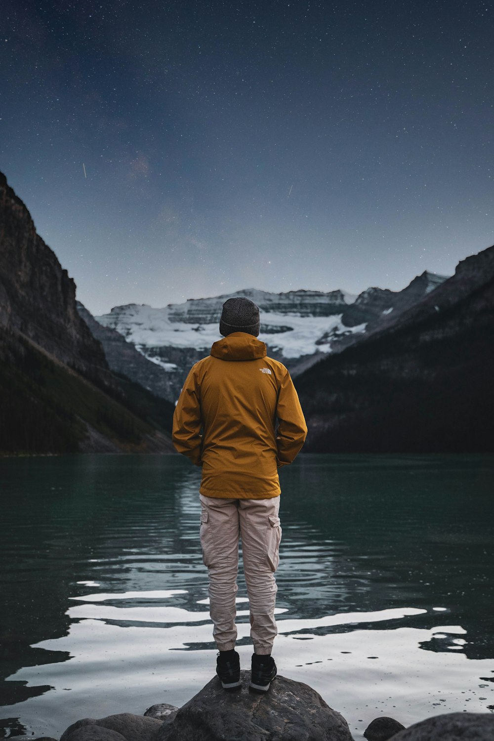 a man standing on top of a rock next to a body of water