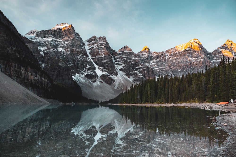 a mountain range is reflected in the still water of a lake