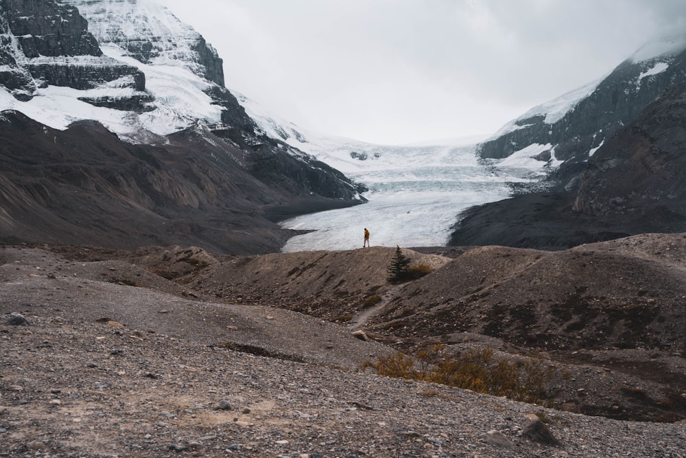 a man standing on top of a mountain next to a glacier