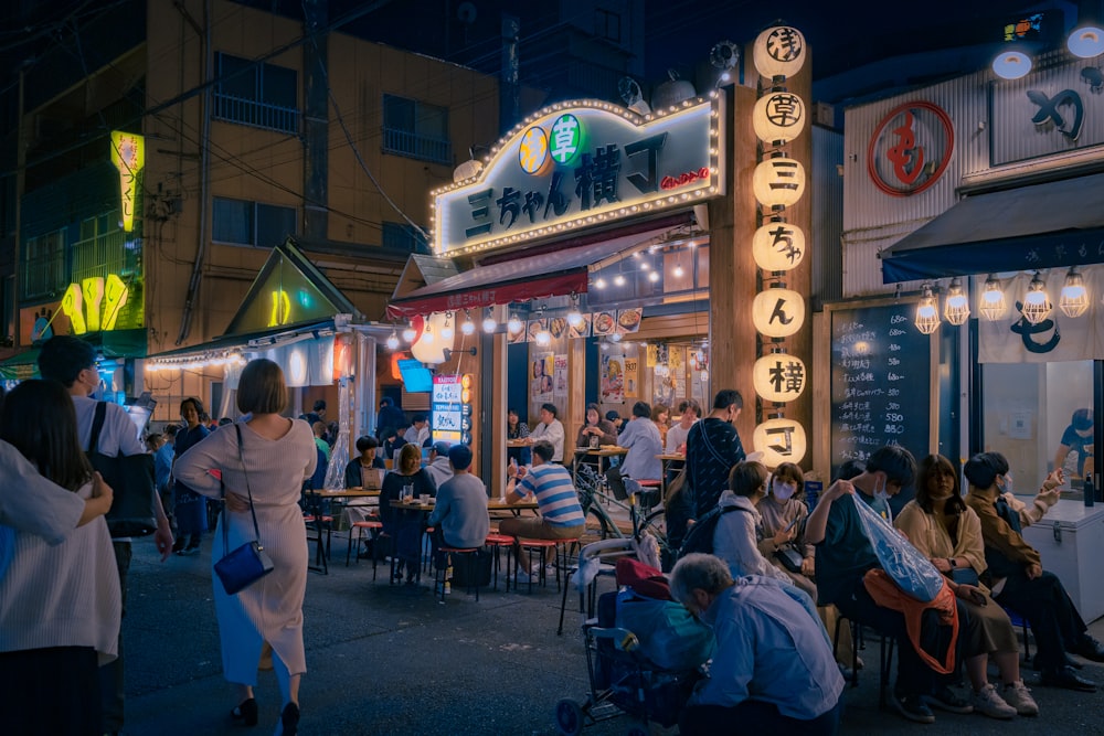 um grupo de pessoas sentadas do lado de fora de um restaurante à noite