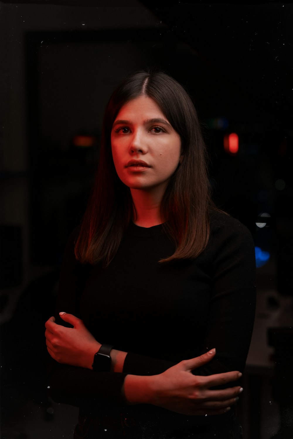 a woman standing with her arms crossed in a dark room