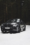 a black bmw suv parked in the snow