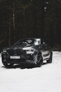 a black bmw suv parked in the snow