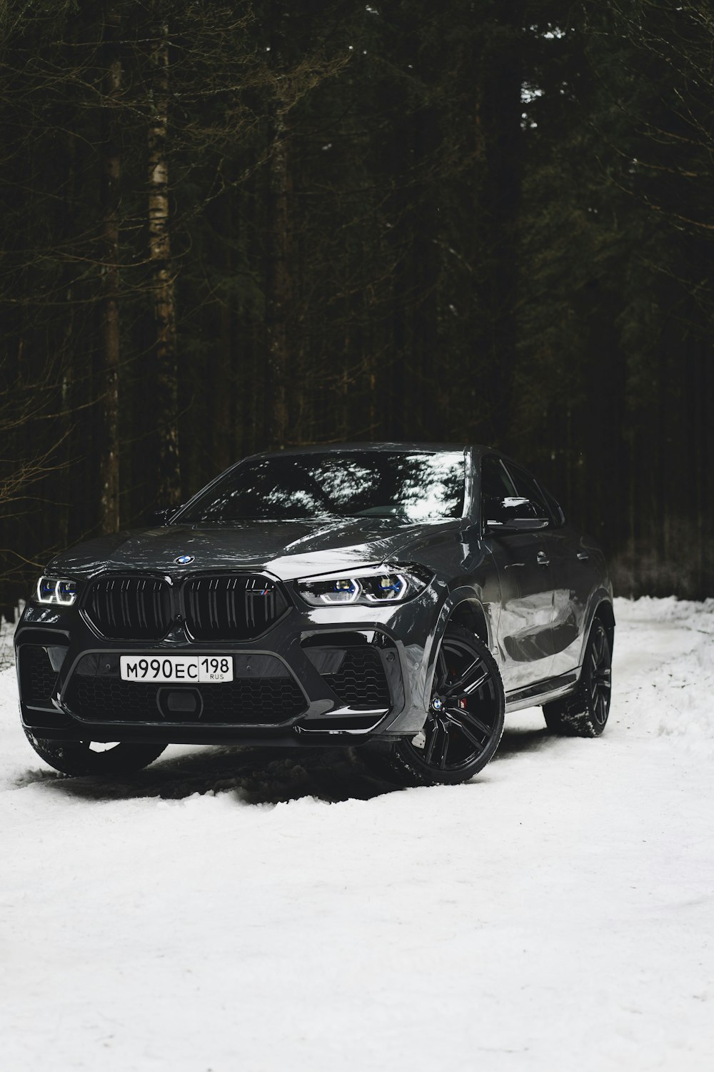 a black bmw suv parked in the snow