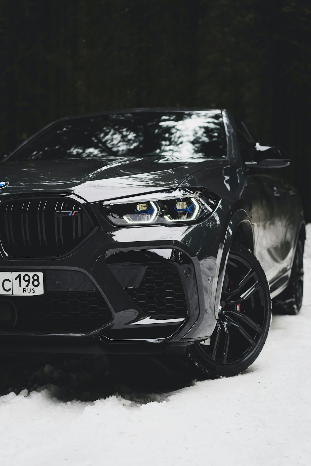 a black bmw suv parked in the snow