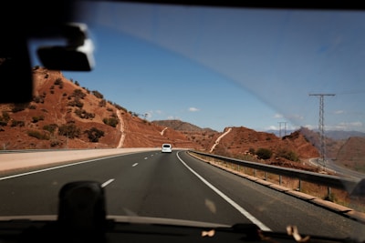 a car driving down a road next to a mountain