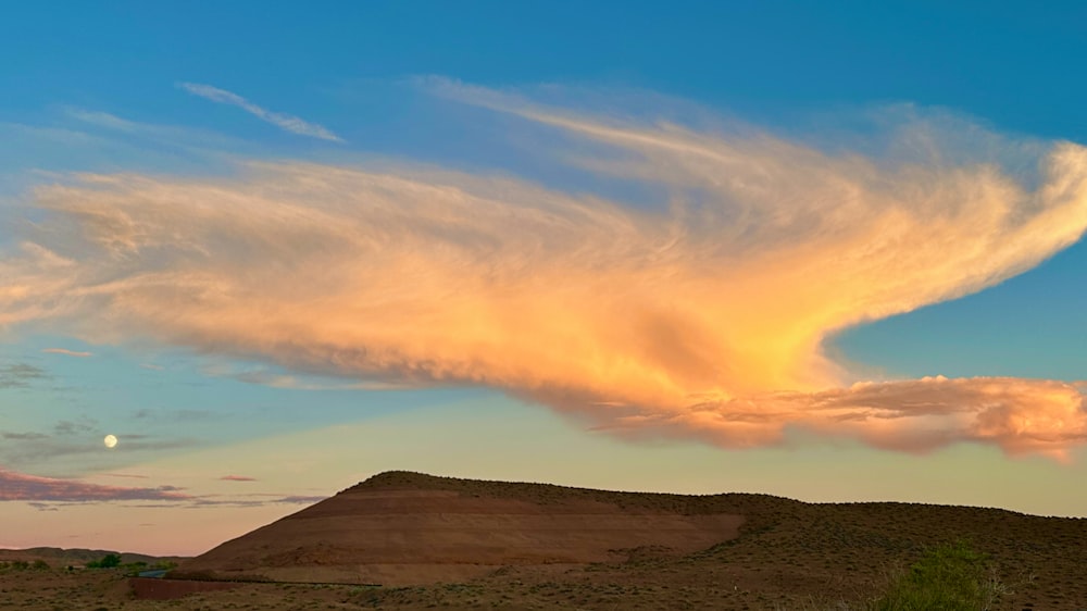 a large cloud in the sky above a hill