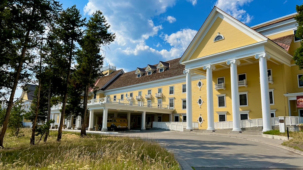 a yellow and white building with columns and trees