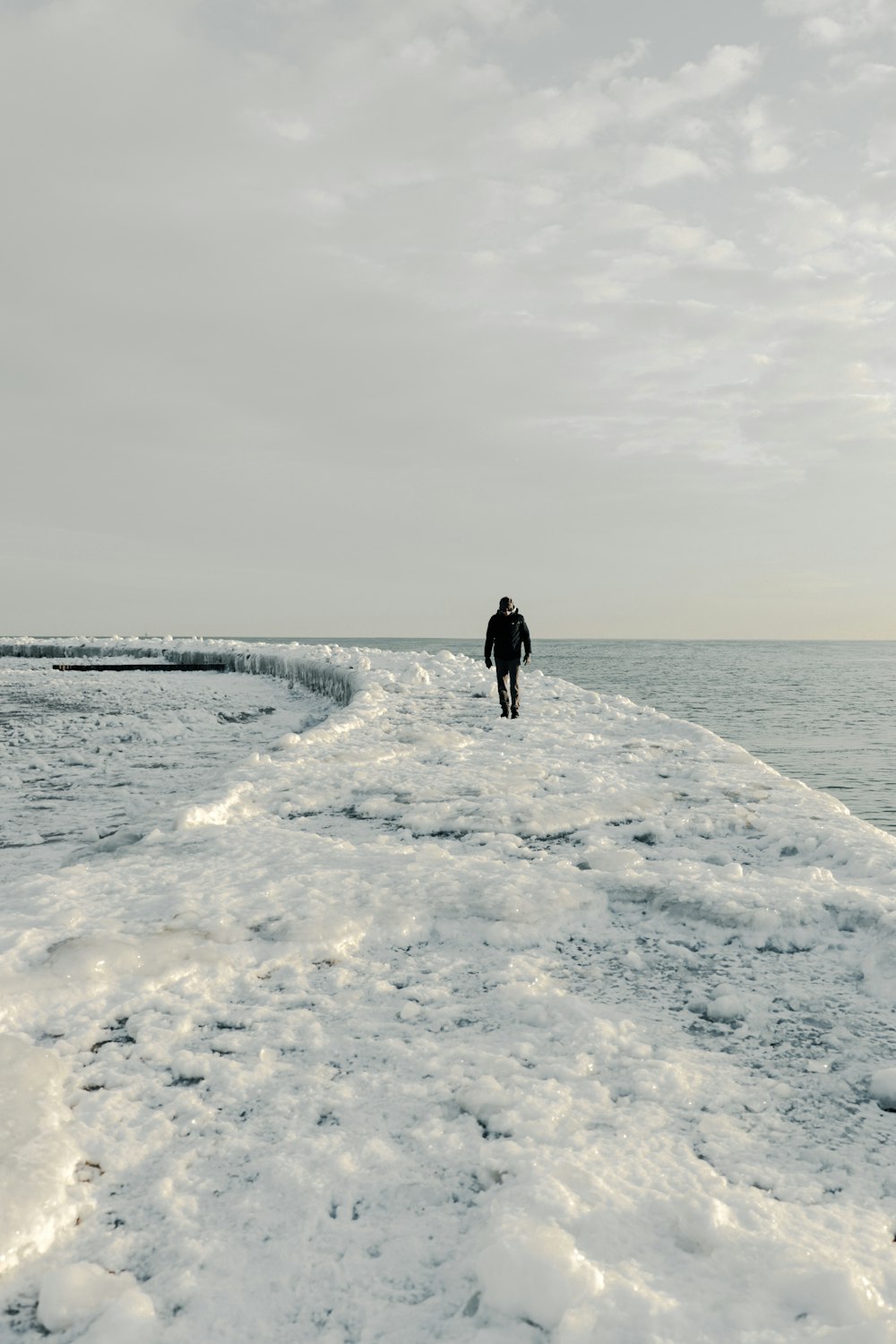 a person walking along a snow covered shore line