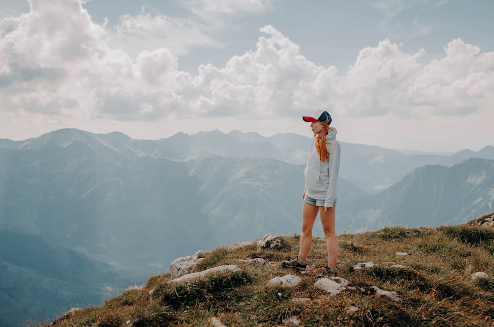 a woman standing on top of a grass covered hillside