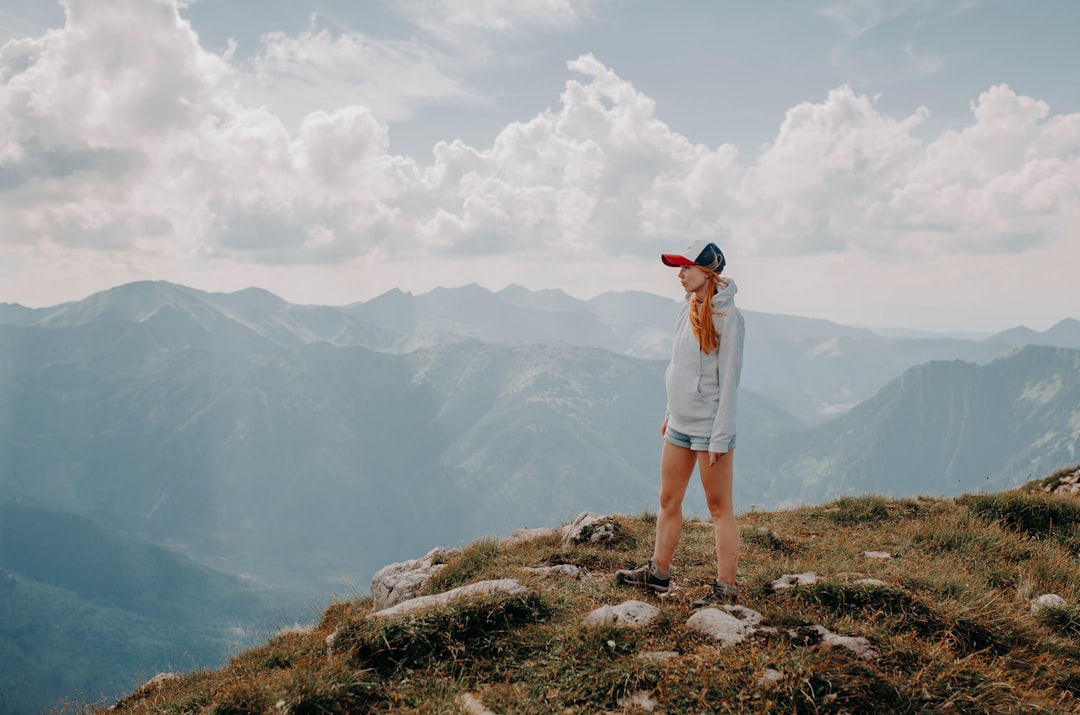 a woman standing on top of a grass covered hillside,