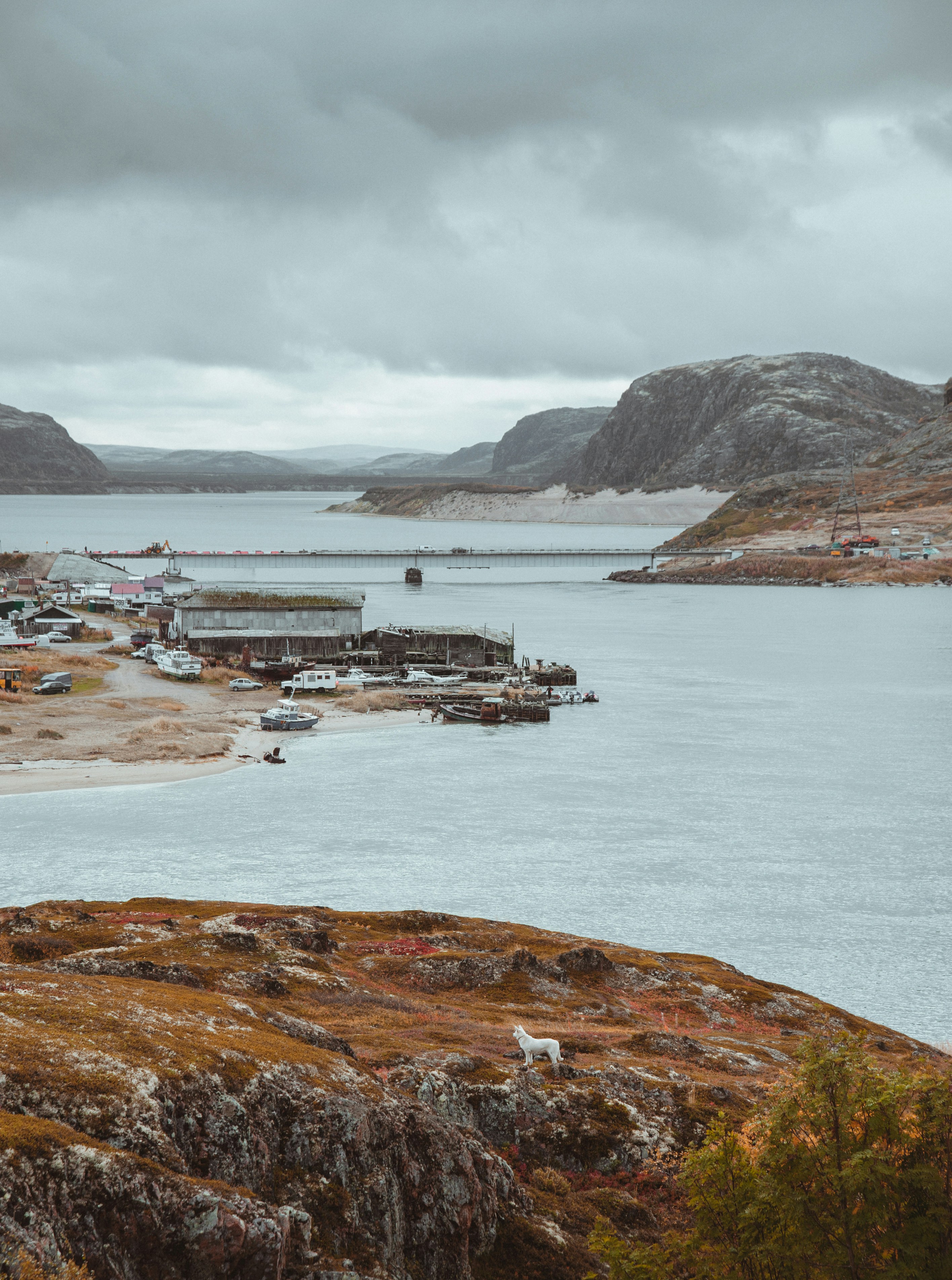 a body of water surrounded by mountains under a cloudy sky