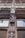 An intricately carved wooden facade features a statue of a person in historical attire. The architecture includes detailed window frames and decorative elements, creating a classic and artistic appearance. The craftsmanship is ornate, reflecting a style from a bygone era.