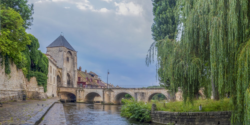 a river flowing under a bridge next to a tall building