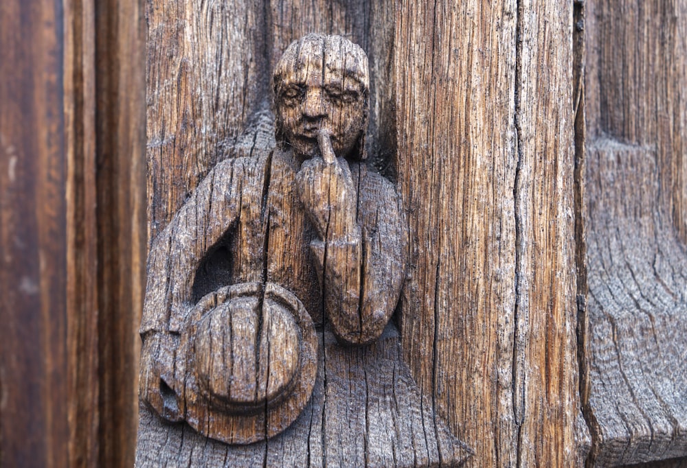 a wooden door handle with a carved figure on it