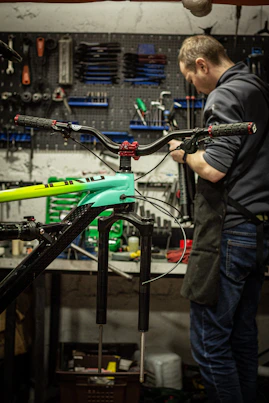 A craftsman carefully assembling a custom bicycle frame in a cozy workshop filled with wooden tools and bike parts.