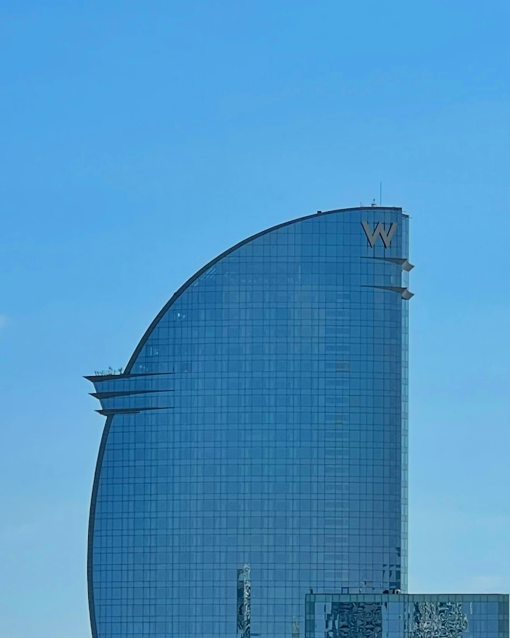 a plane flying over a tall building with a sky background