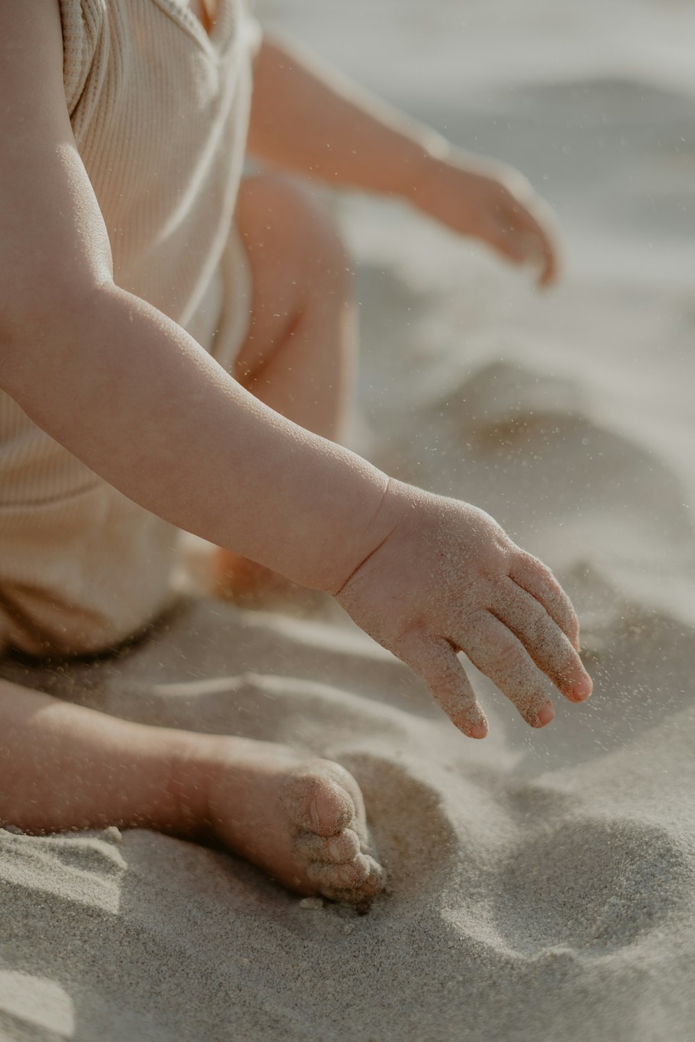 a baby sitting in the sand on the beach