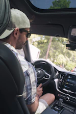 A happy passenger using a smartphone app inside a modern car in a sunny city street.