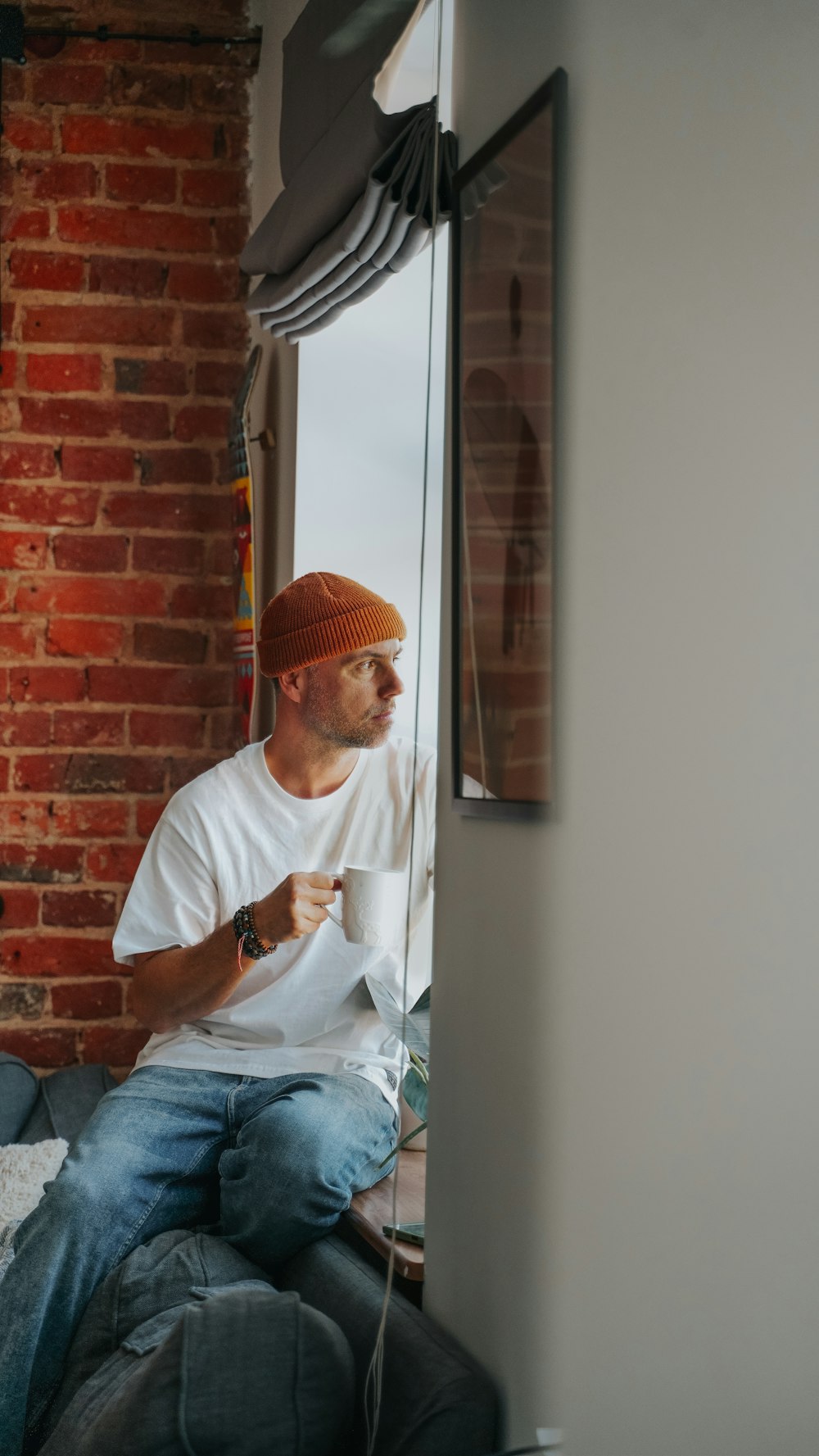 a man sitting on top of a bed next to a window