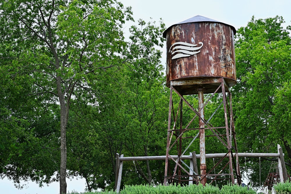an old rusted water tower in the middle of a forest