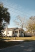 a house with a white picket fence and trees in front of it