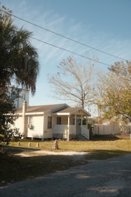 a house with a white picket fence and trees in front of it