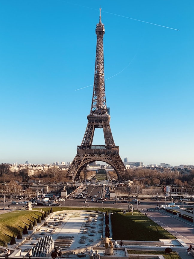 A picturesque view of the Eiffel Tower with surrounding Parisian cityscape under a clear blue sky.