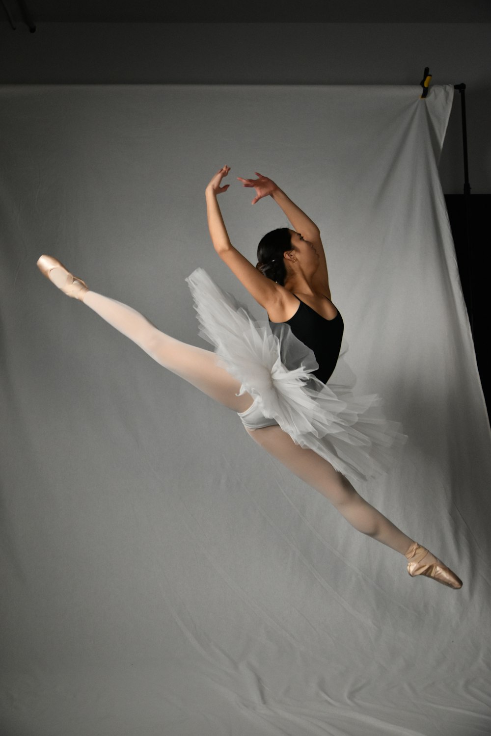 Una bailarina con leotardo negro y tutú blanco