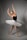 A dancer poses gracefully in a ballet position. She wears a black leotard paired with a white tutu, her arms elegantly extended above her head. The background is a plain, soft gray, and her feet are in pointe shoes, reflecting the discipline and artistry of ballet.