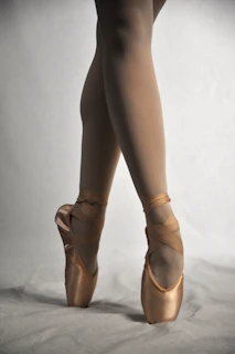 A close-up of feet in colorful dance shoes moving gracefully across a polished wooden floor.
