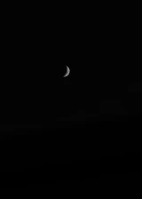 A calm night sky with a crescent moon casting soft light over a quiet landscape.