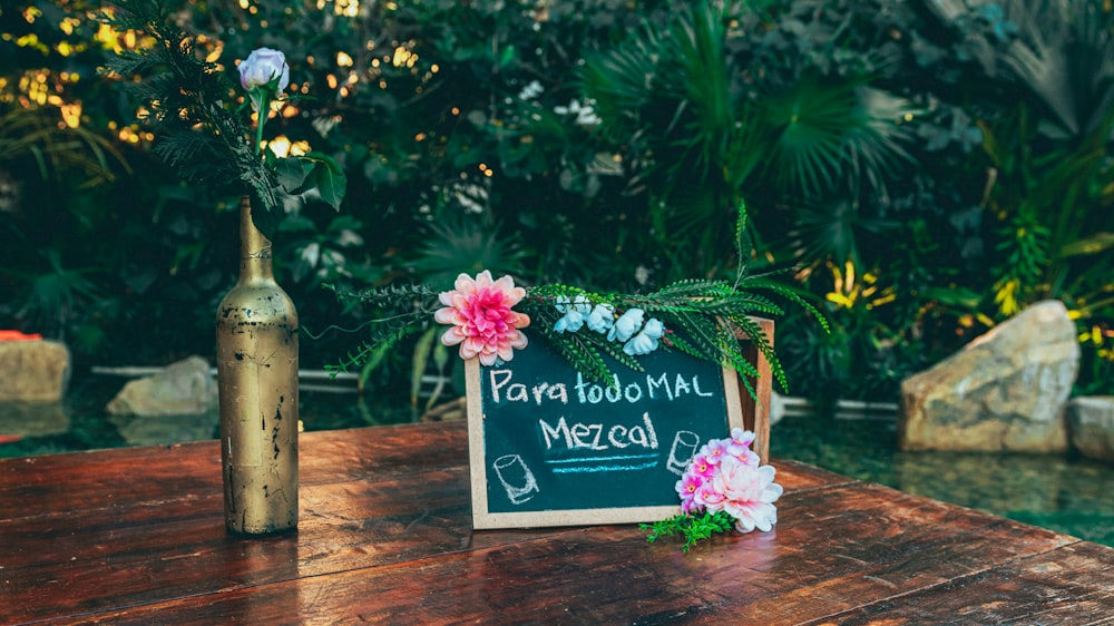 a wooden table topped with a sign and flowers