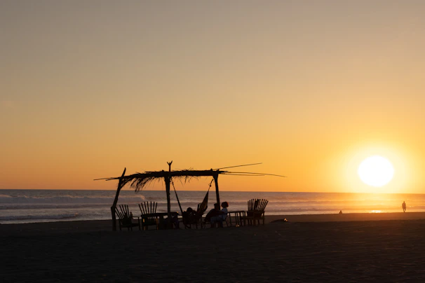 Sunset over the Costa Rican coast with silhouettes of digital nomads relaxing and chatting outdoors.