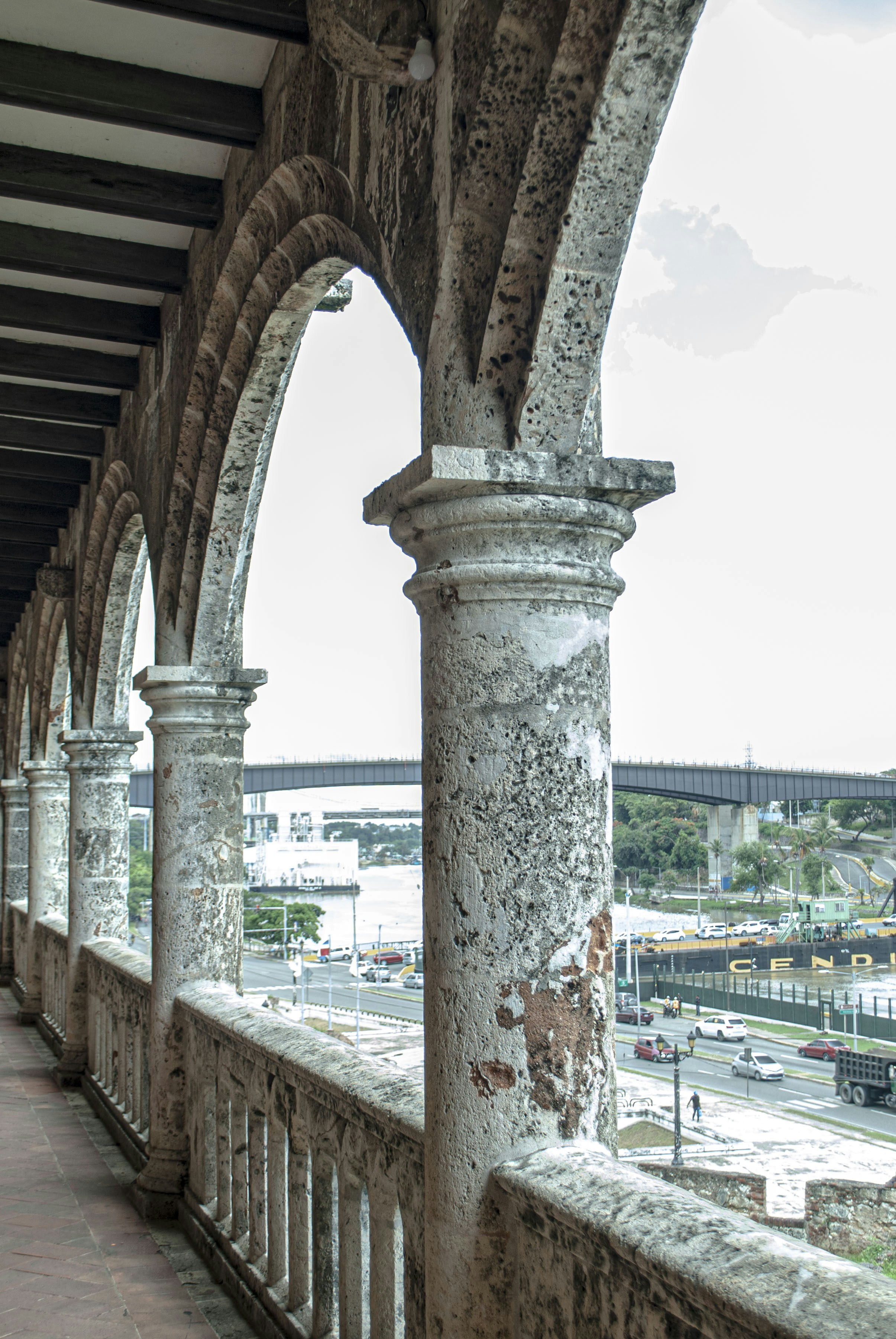 a stone wall with arches and a clock tower in the background