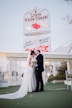 a bride and groom standing in front of a sign