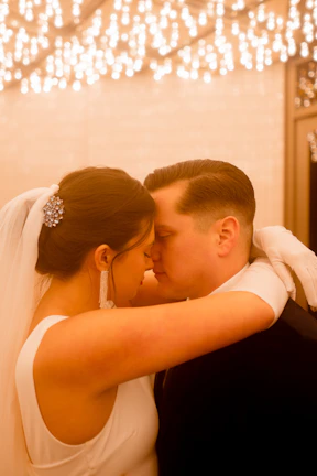 A bride and groom sharing a quiet, intimate moment under soft, moody lighting.