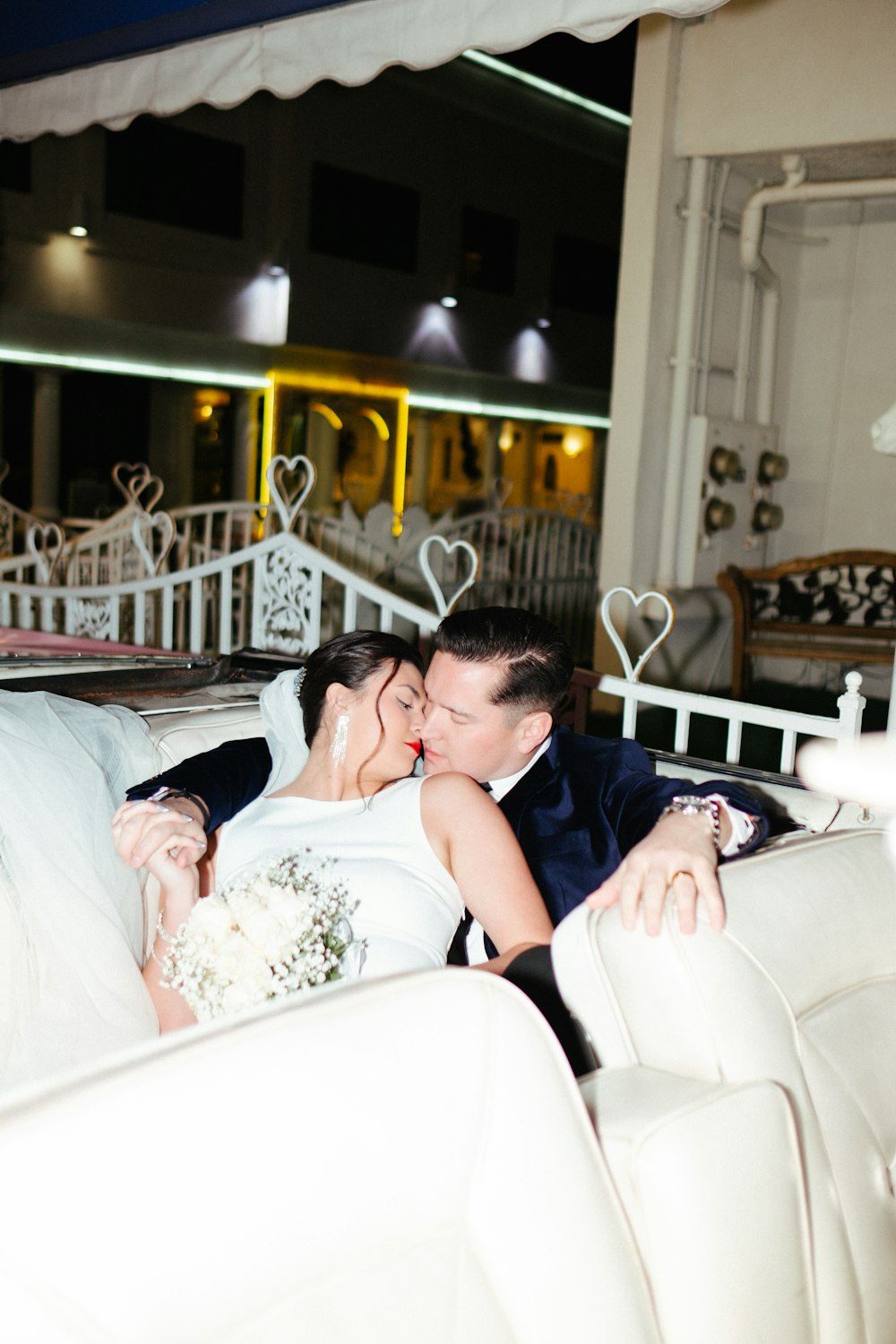 a bride and groom kissing on a white couch